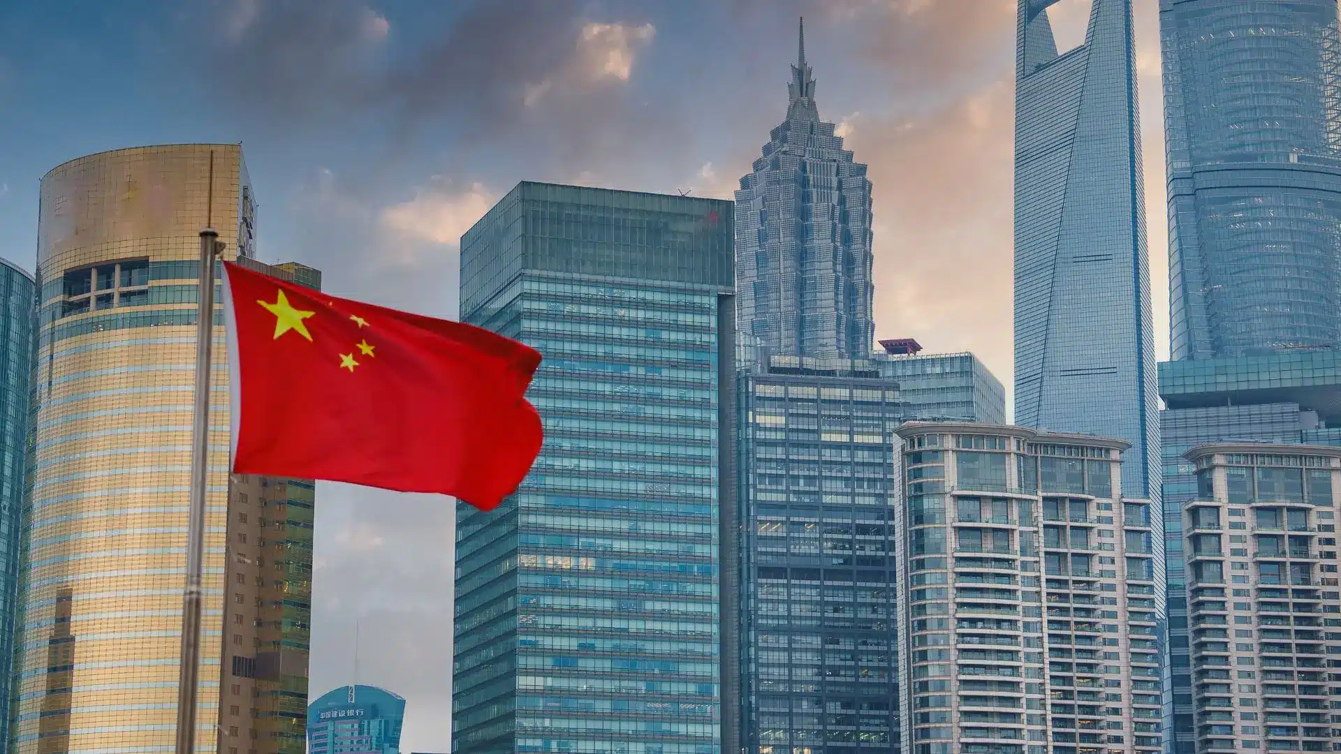 Chinese flag waving with modern skyscrapers and financial district skyline in the background.