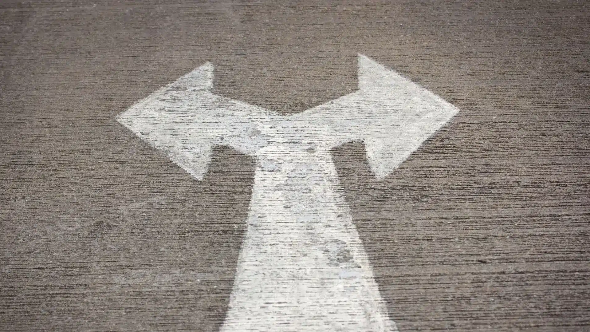 Road surface marked with a white arrow splitting into two directions, symbolising the choice between internationalised and domestic access routes in China's futures markets.
